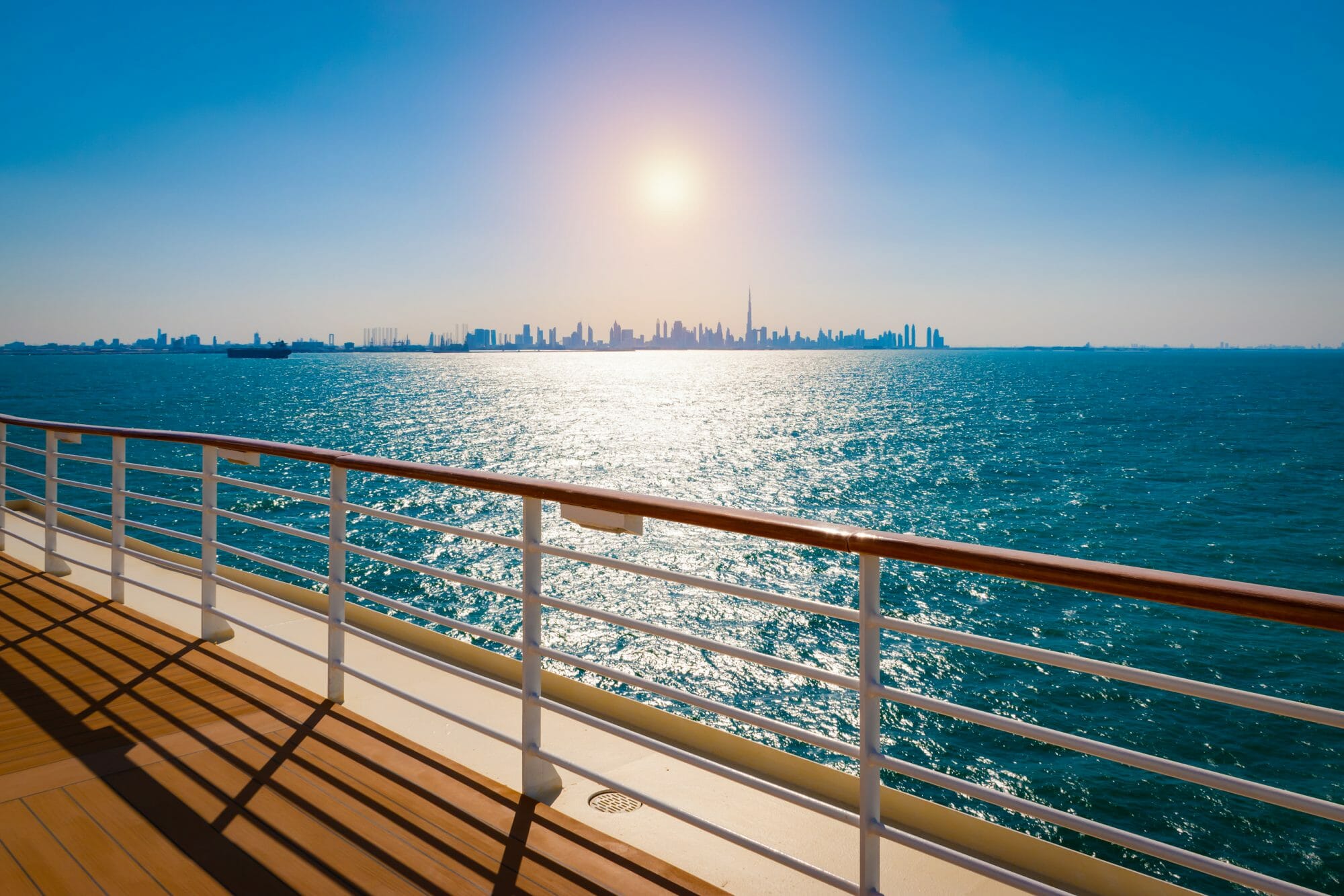 Spektakulärer Blick von der Reeling eines Kreuzfahrtschiffes auf das glitzernde Meer und die beeindruckende Skyline von Dubai mit dem Burj Khalifa im Sonnenlicht. Ein exklusives Reiseerlebnis, das Luxus, Entspannung und das Flair einer Kreuzfahrt in den Vereinigten Arabischen Emiraten vereint – perfekt für Traumreisen und unvergessliche Momente auf hoher See. Gerlingen und Stattgart bei mhs buchen.